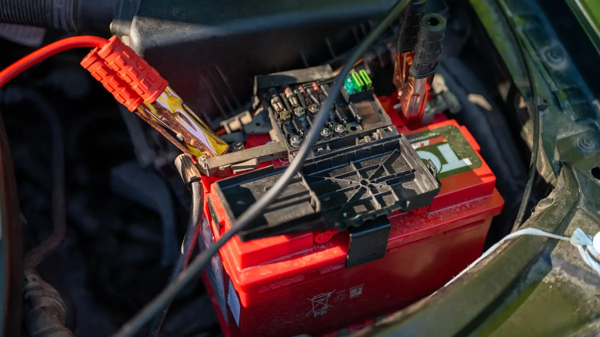 Vehicle battery with red cables and clamps attached