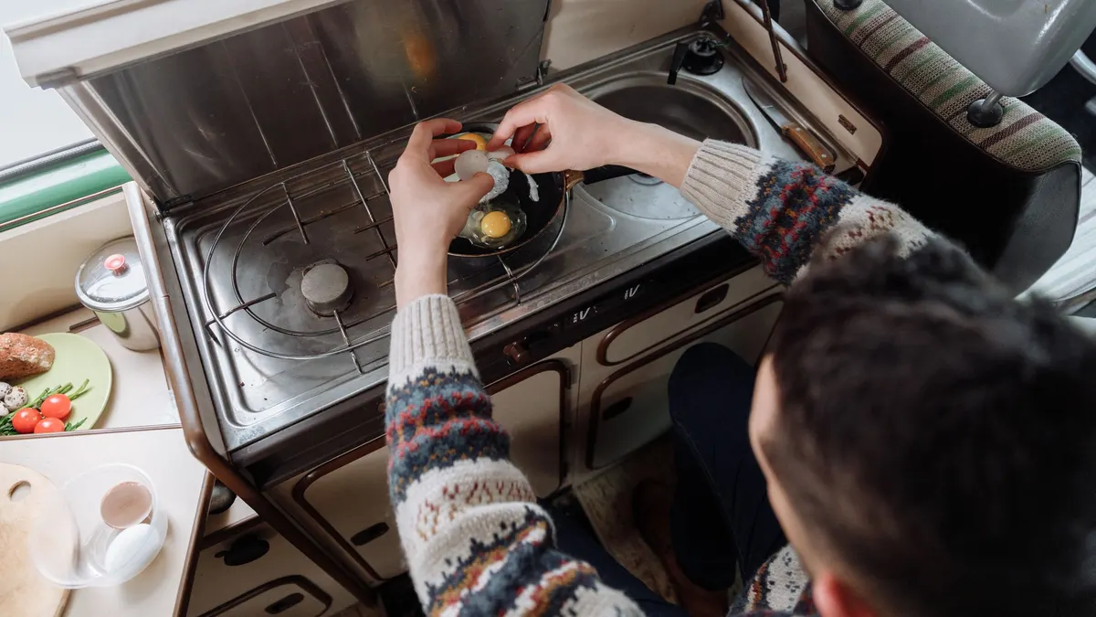 Person frying eggs on a compact camper stove