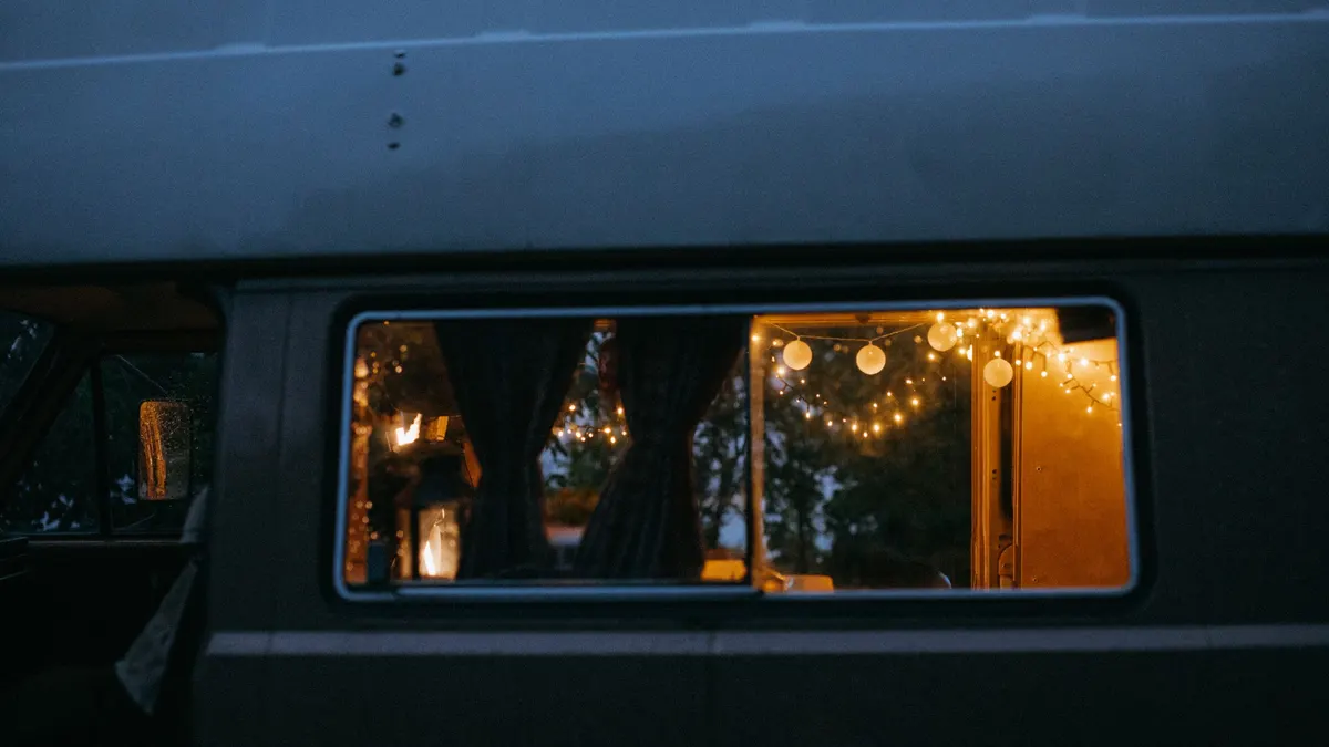 Camper van window lit by warm string lights at night