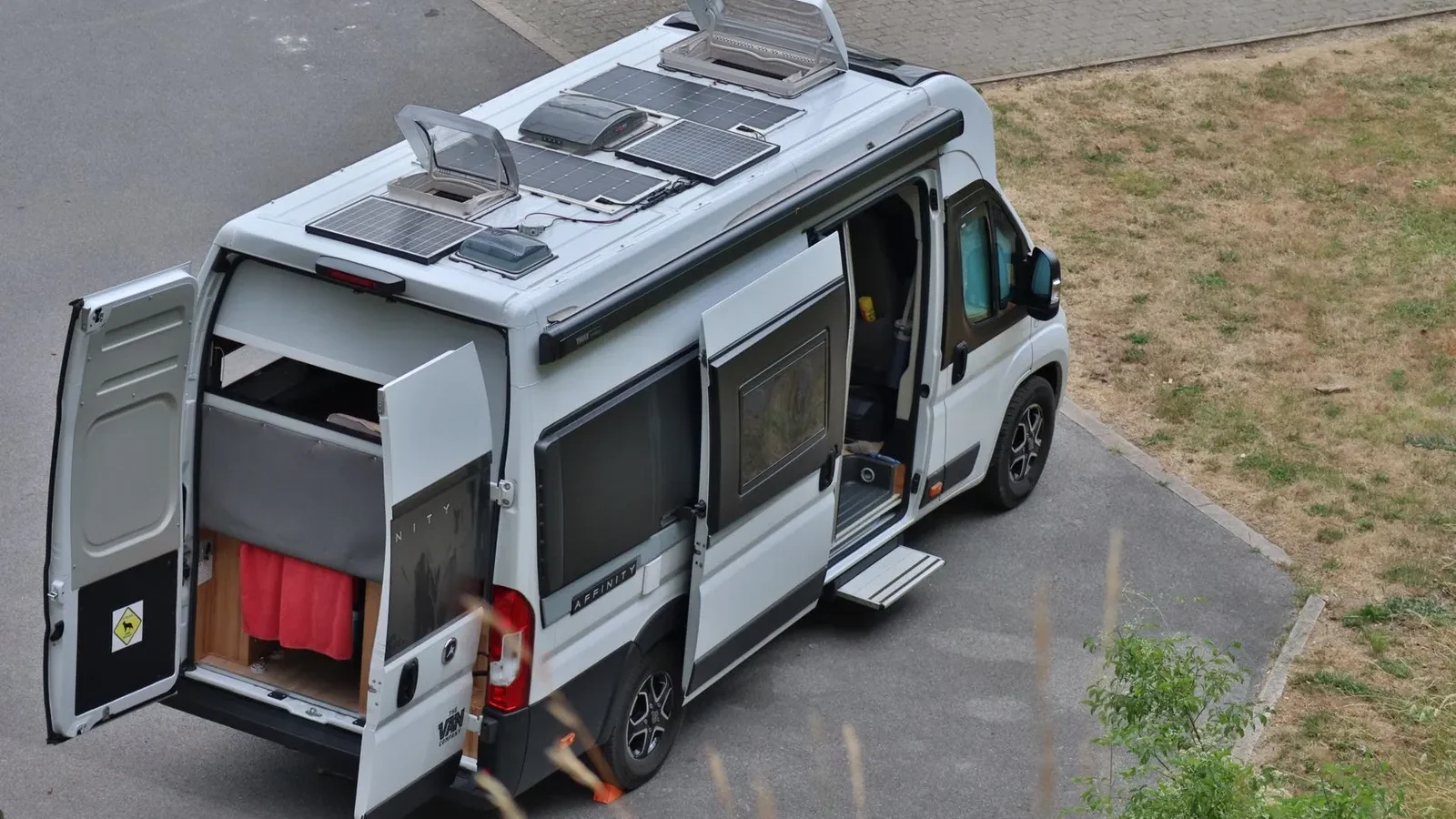 Camper van with rooftop solar panels parked with its side and rear doors open