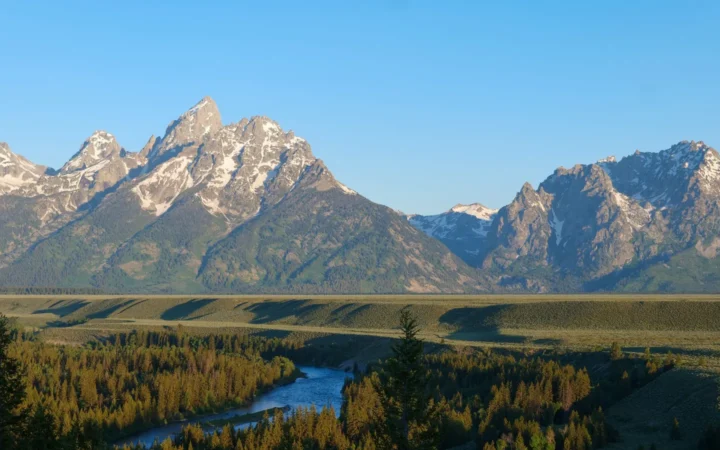 The Teton Range rising above forest and a winding river valley