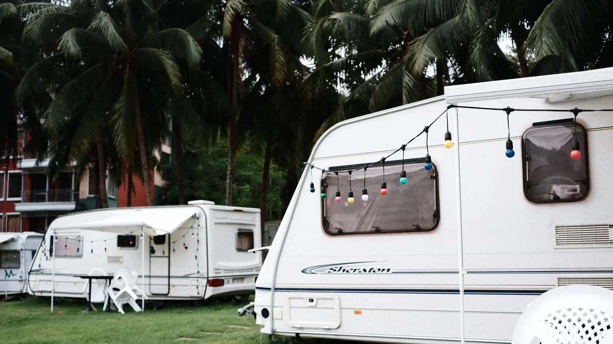 Travel trailers parked at a grassy campground with string lights