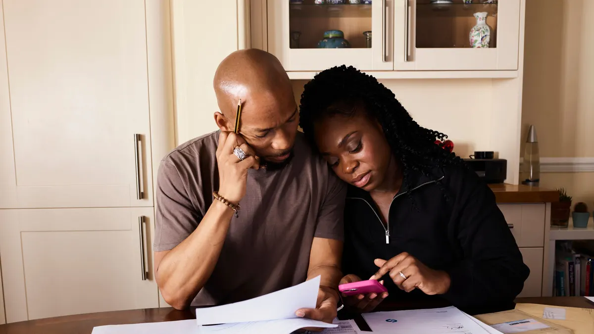 Couple reviewing paperwork and a calculator at a kitchen table