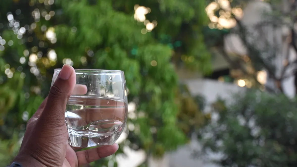 Hand holding a clear glass of water outdoors