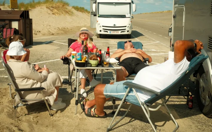 Group relaxing in camp chairs beside a parked RV