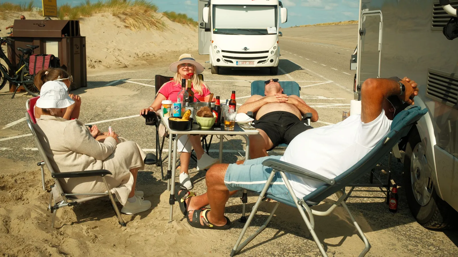 Group relaxing in camp chairs beside a parked RV