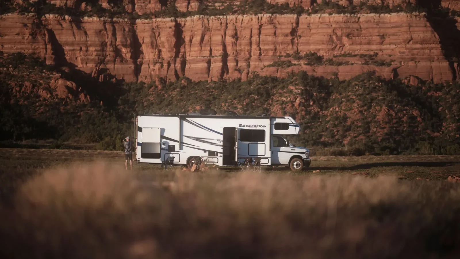 Motorhome parked on a quiet site below red sandstone canyon walls at golden hour