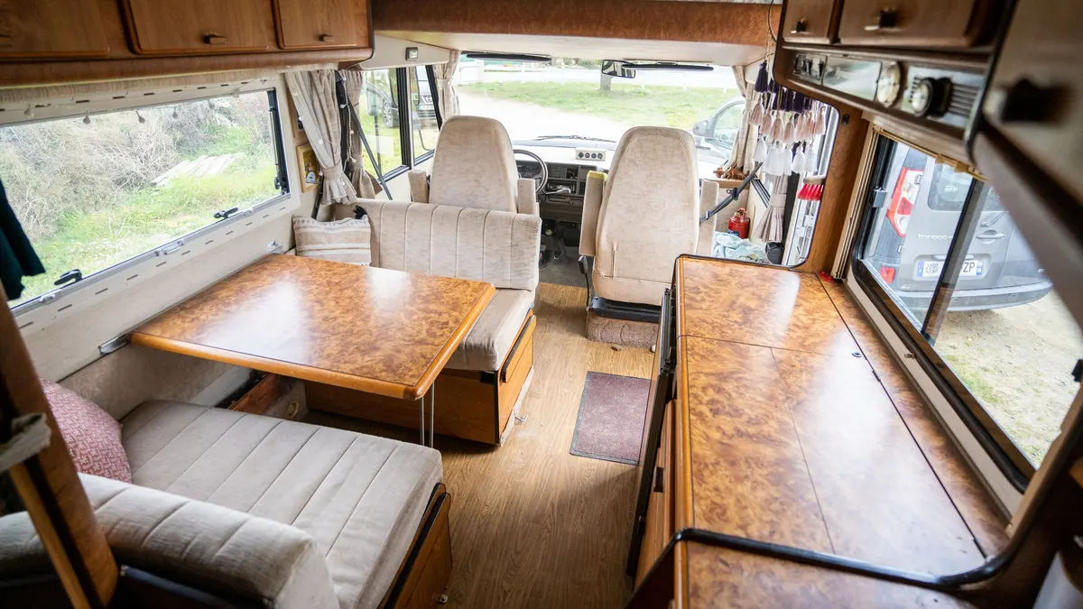 Bright RV interior with a dinette table, seating and galley cabinets
