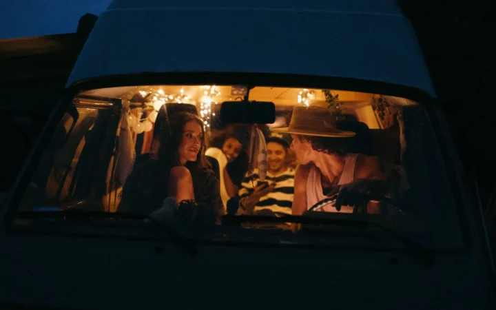 Friends inside a warmly lit camper van at night