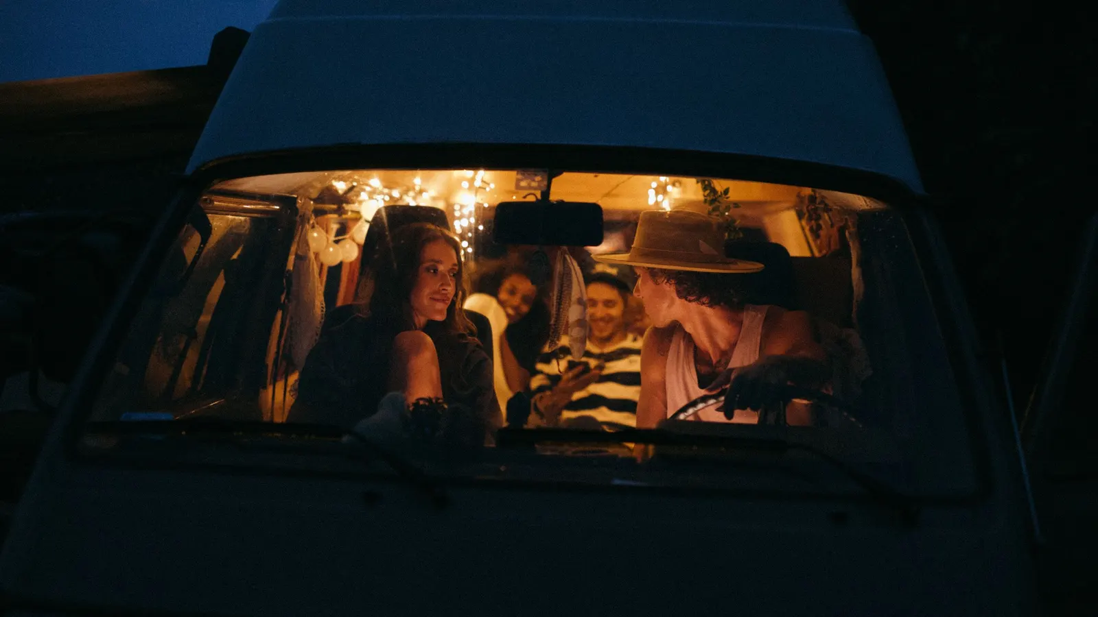 Friends inside a warmly lit camper van at night