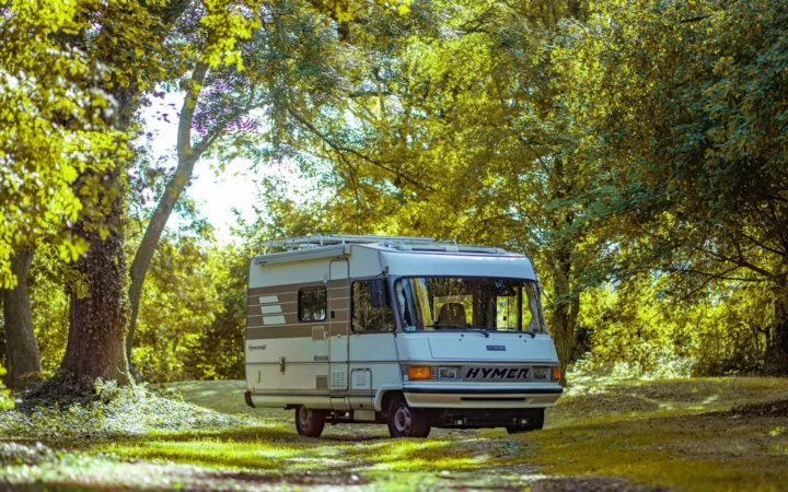 Vintage motorhome parked in a sunlit forest clearing