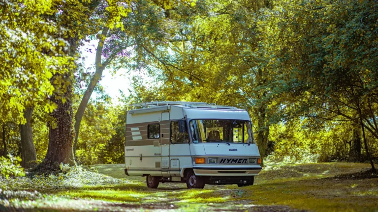 Vintage motorhome parked in a sunlit forest clearing