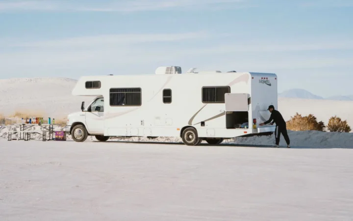 Class C motorhome parked in bright sun on an open desert flat