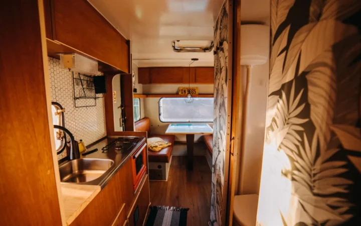 Warm-toned travel trailer interior with a galley sink and cabinets