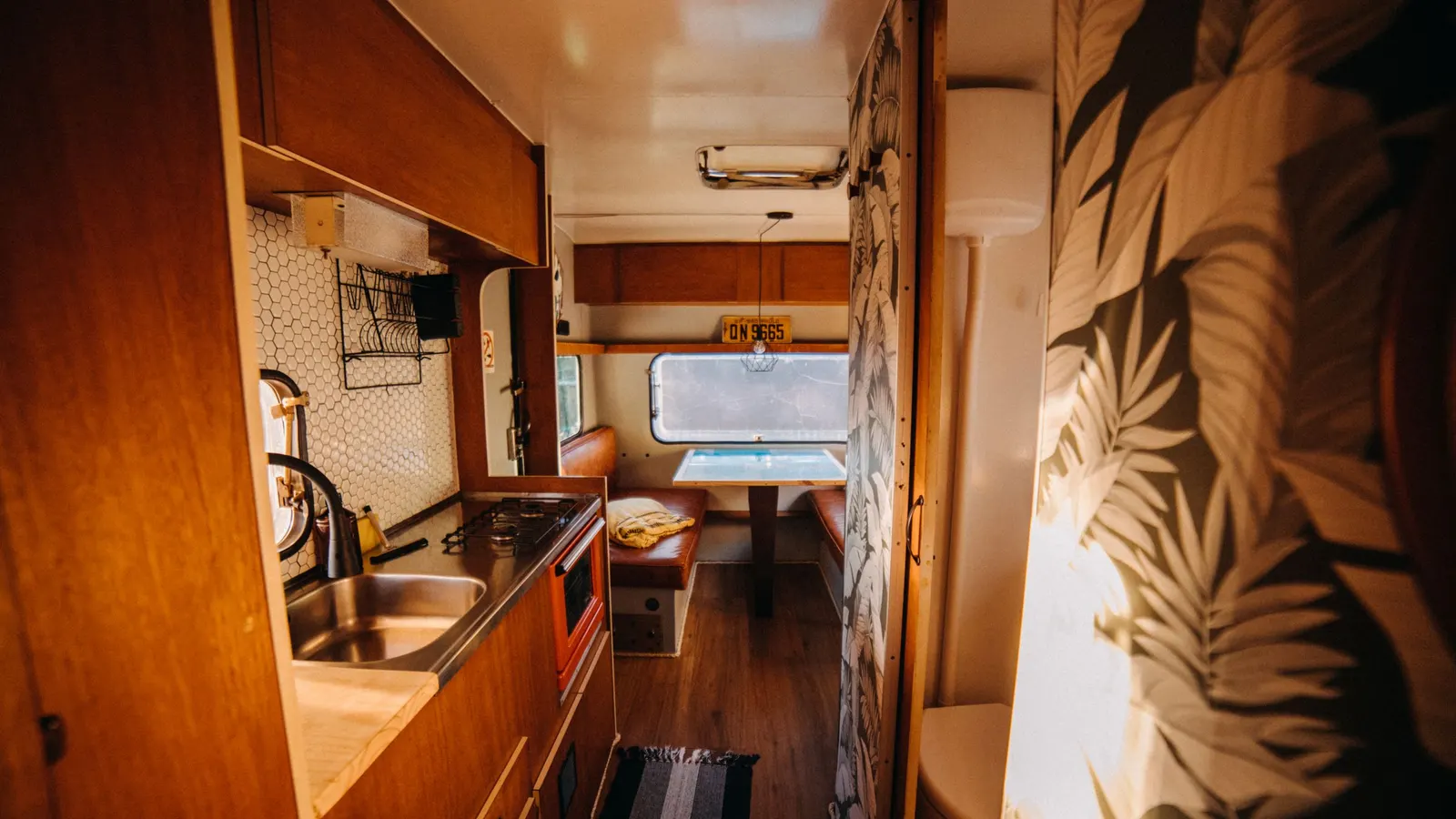Warm-toned travel trailer interior with a galley sink and cabinets