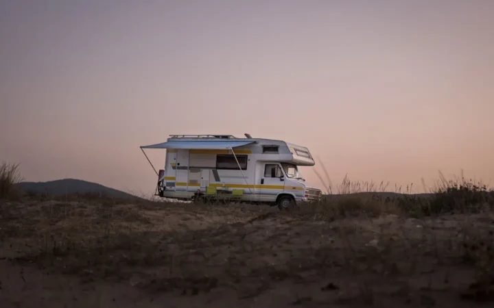 Class C motorhome parked on open ground at dusk