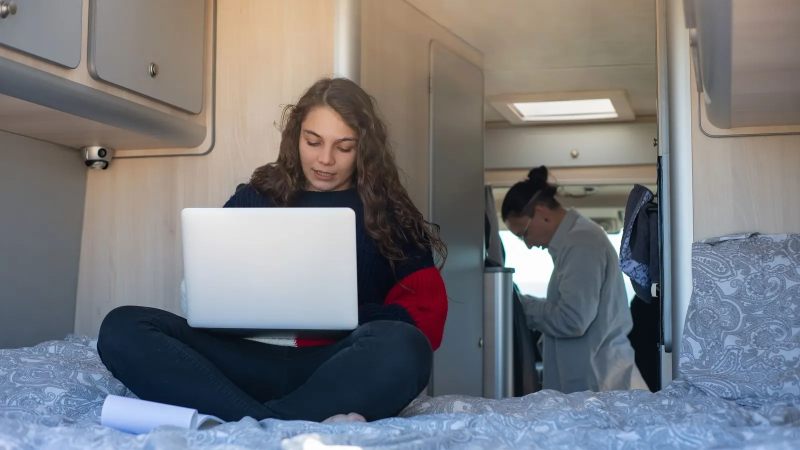 Woman working on a laptop while sitting cross-legged inside a camper