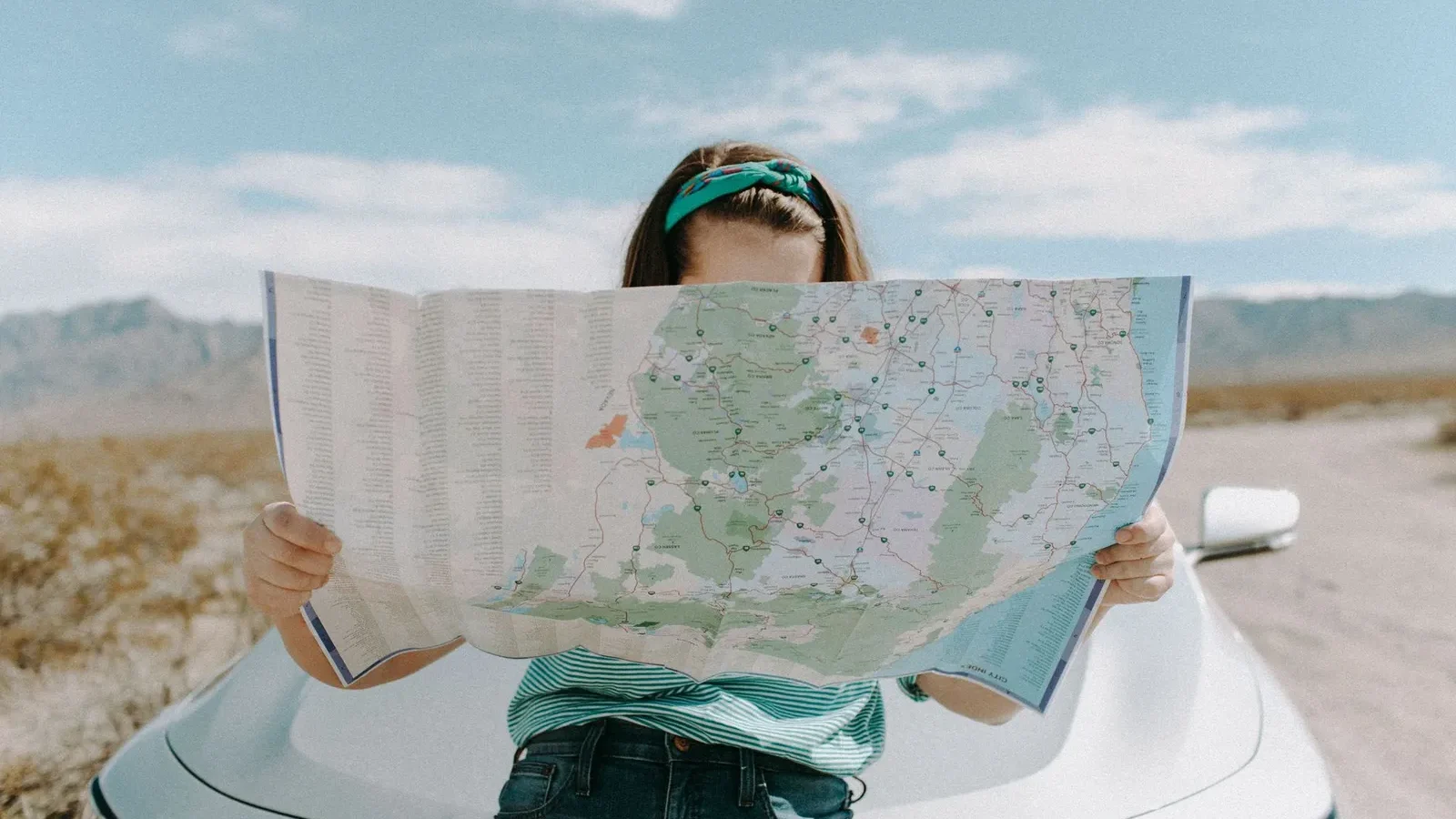 Traveler holding a large paper road map while planning a route