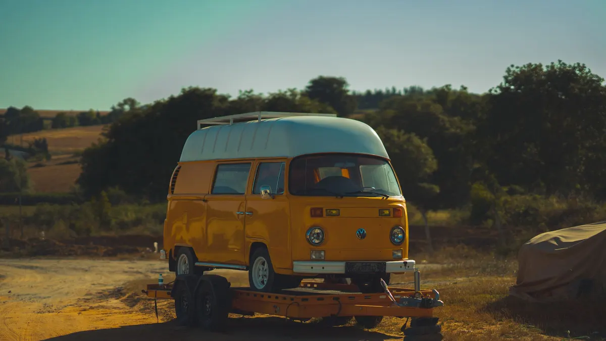 Yellow camper van parked in a dry, sunny summer landscape