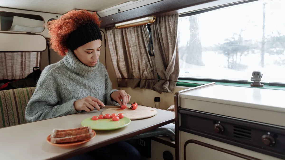 Traveler preparing fresh food at the table inside a camper van