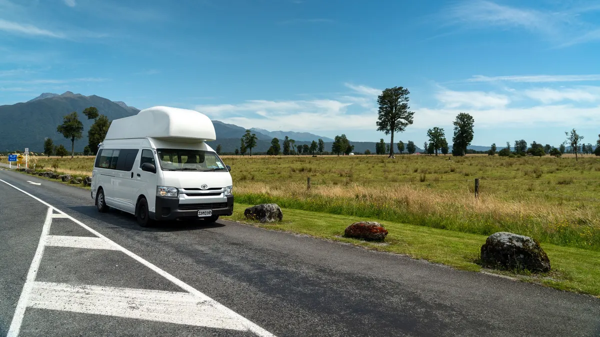 Camper van on an open road with mountains in the distance