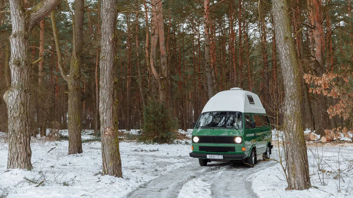 Green camper van on a snowy forest road in winter