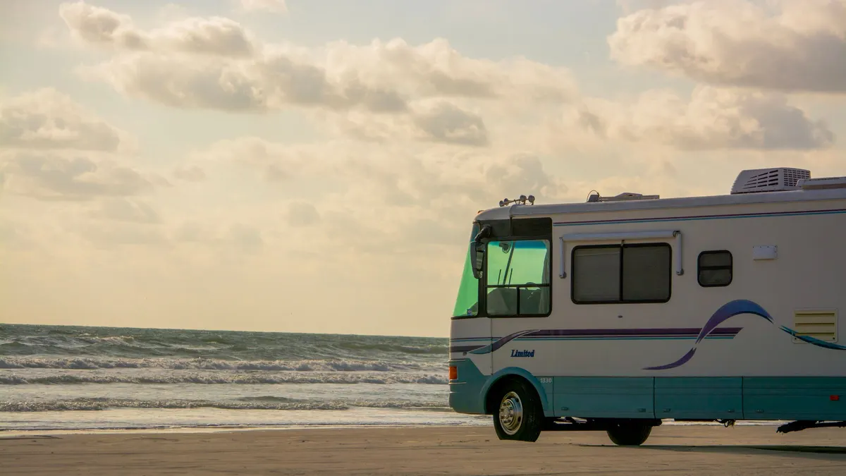 Class A motorhome parked by the sea at sunset
