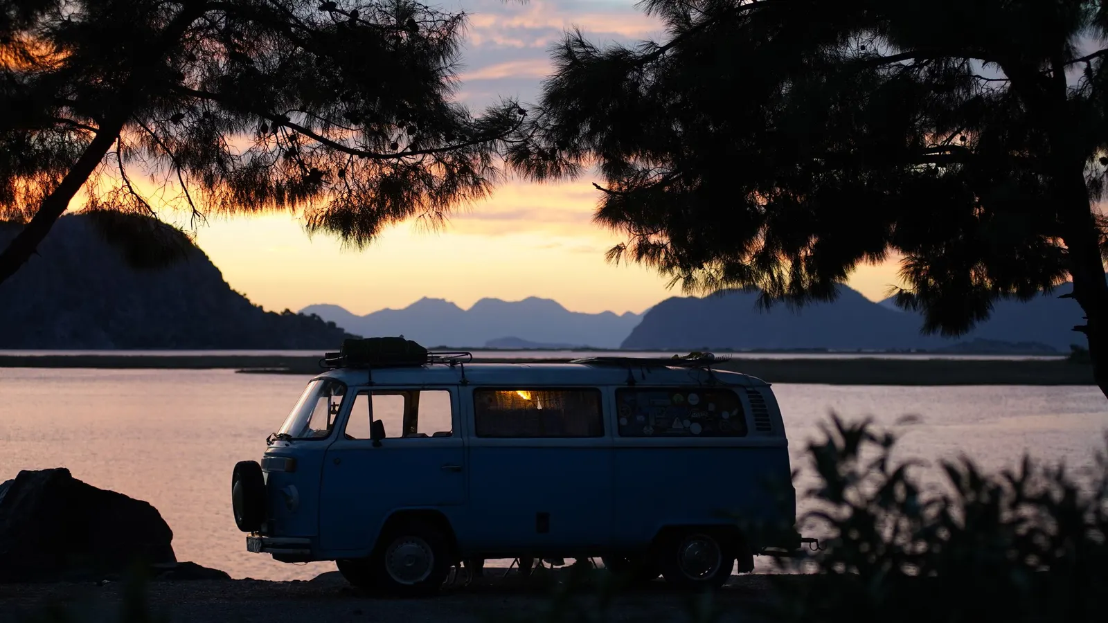 Camper van parked by a lake at sunset, the kind of free or low-cost stay that shapes the cost of full-time RVing