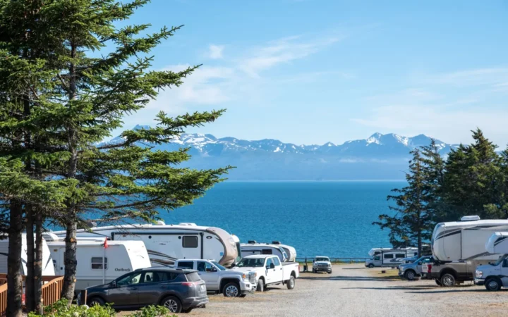 RVs parked at a coastal campground with mountains across the water