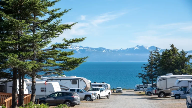 RVs parked at a coastal campground with mountains across the water
