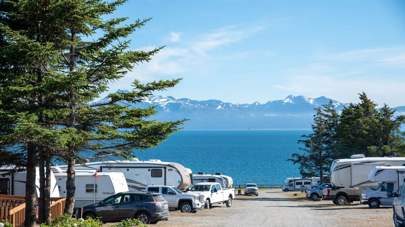 RVs parked at a coastal campground with mountains across the water