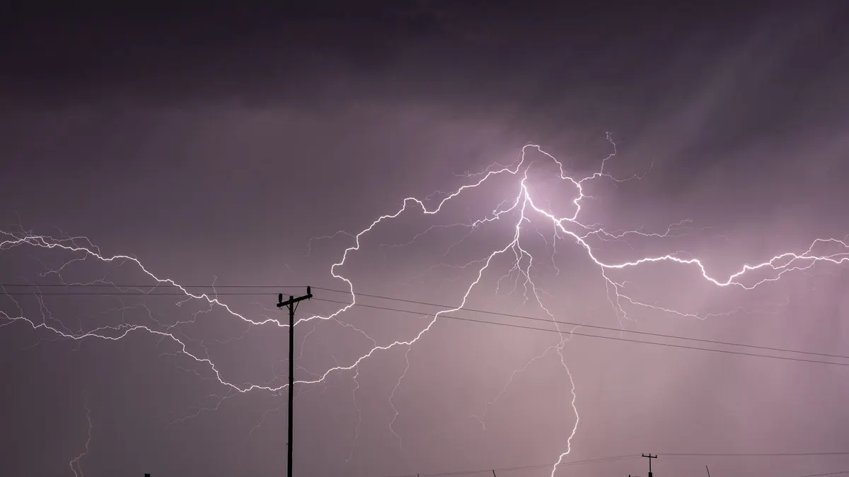 Lightning bolts over power lines at night