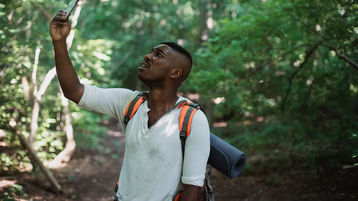 Man in the woods holding his phone up to find signal