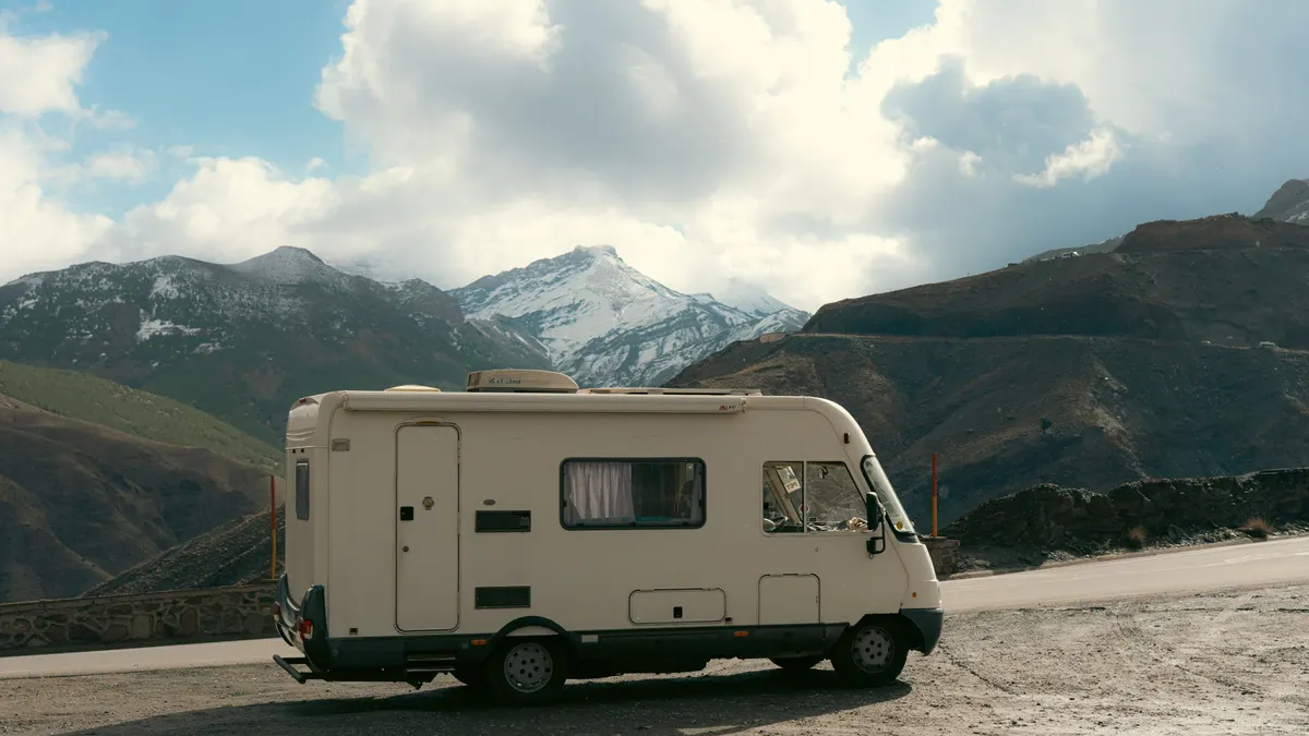 Motorhome parked on a mountain road with peaks behind