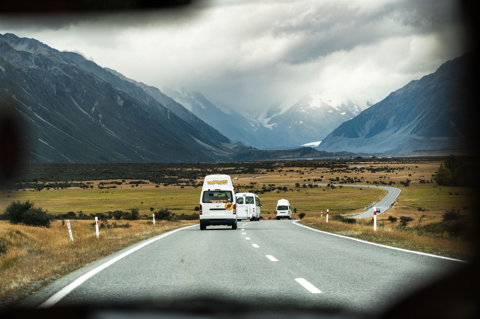 A motorhome driving along a mountain road under heavy cloud