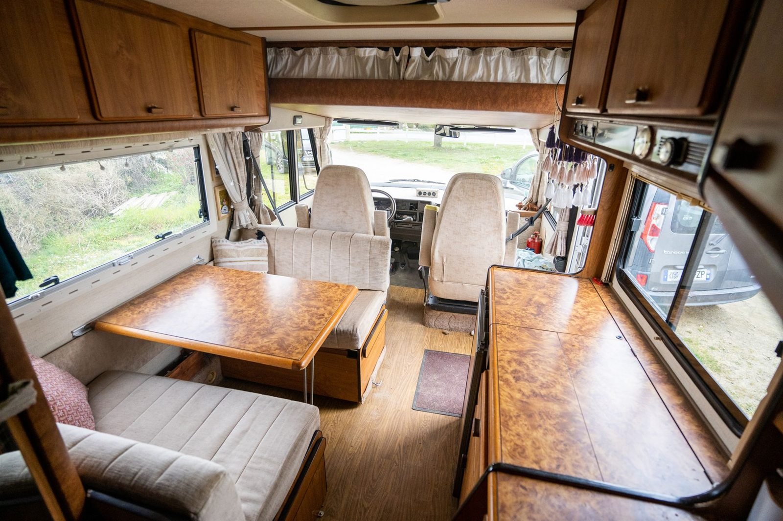The interior of an RV showing a dinette, cabinets and windows