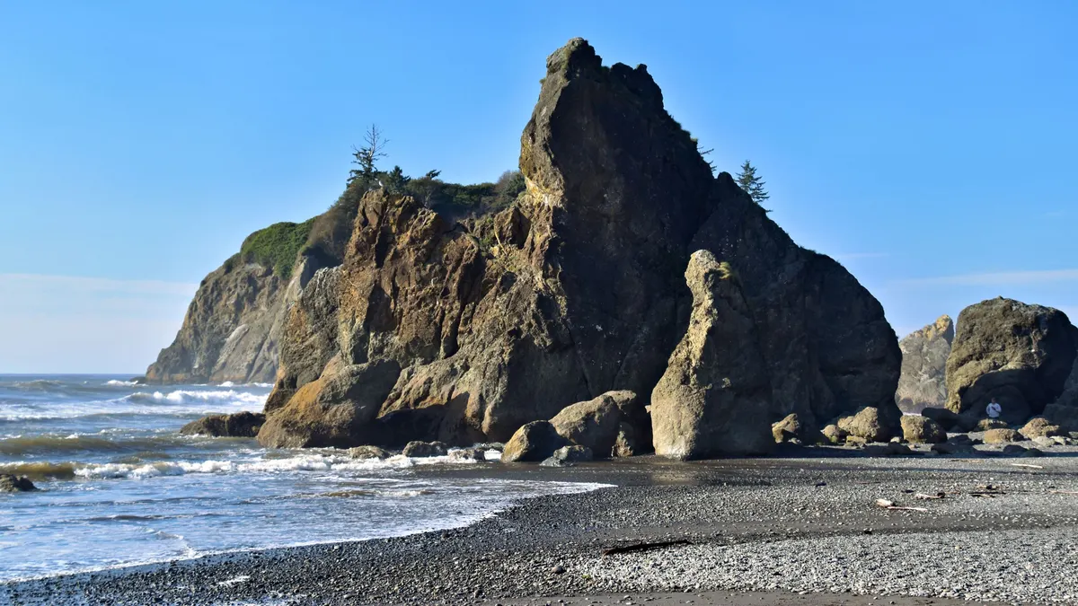Rocky sea stacks on a Pacific beach under blue sky