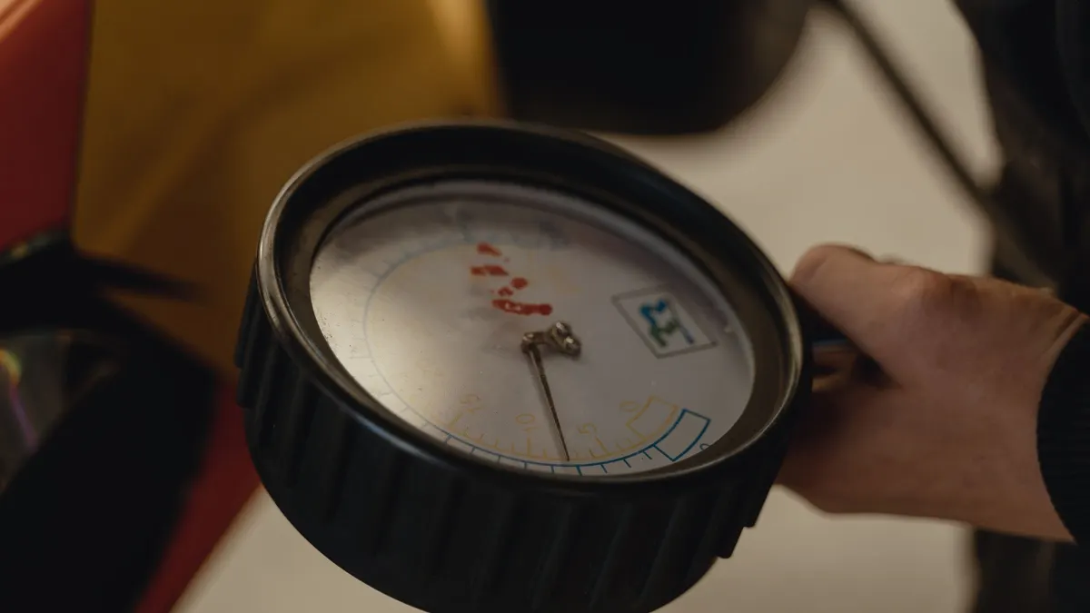 Hand holding an analog pressure gauge