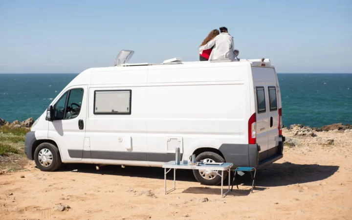 White camper van parked on a sunny coastal bluff, the kind of hot, exposed site where an RV air conditioner works hardest