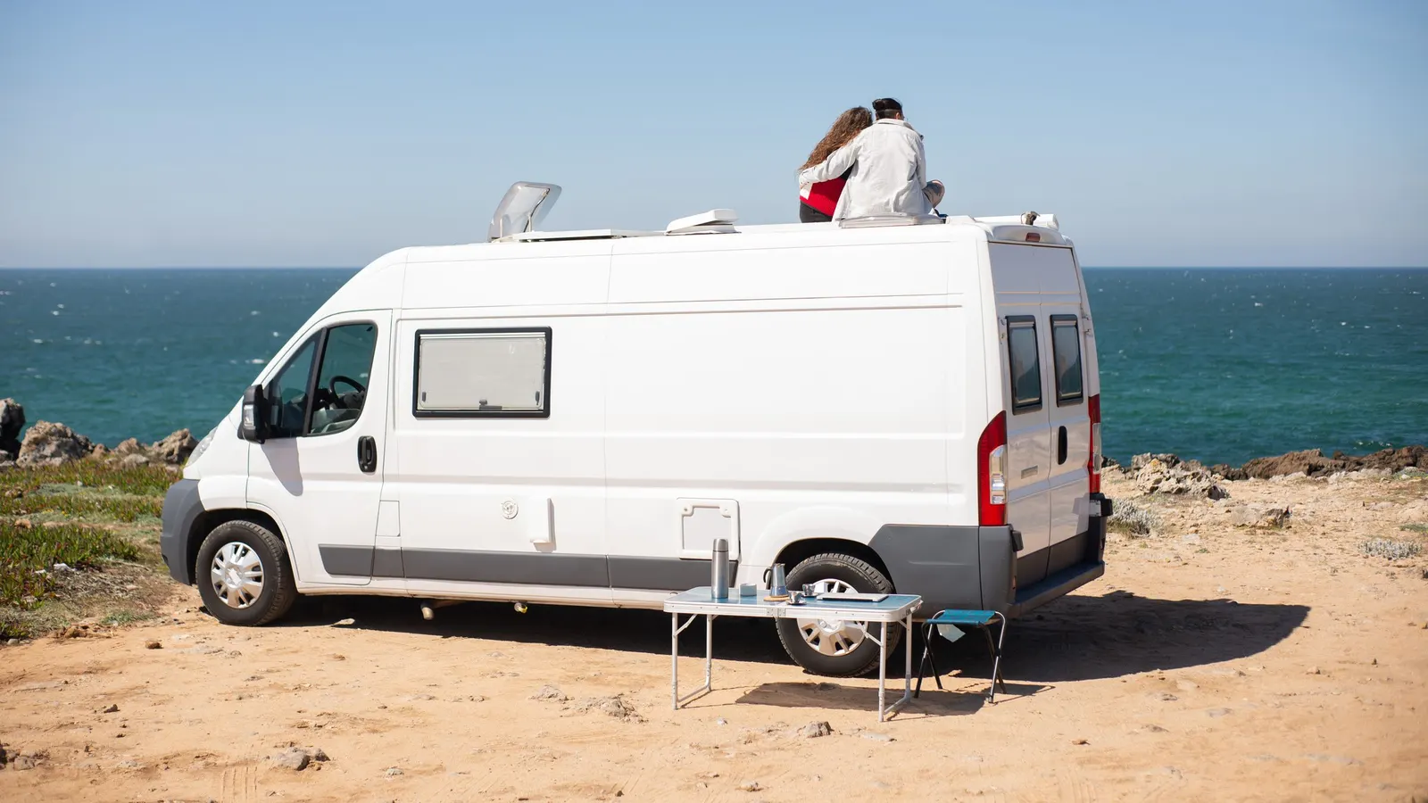 White camper van parked on a sunny coastal bluff, the kind of hot, exposed site where an RV air conditioner works hardest
