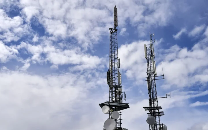 Cell towers with antennas against a cloudy sky
