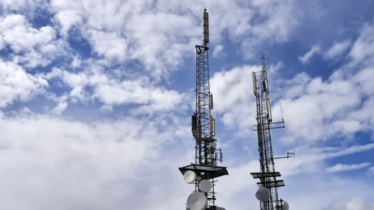 Cell towers with antennas against a cloudy sky
