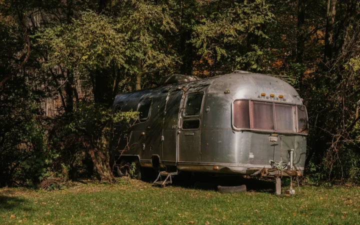 Silver travel trailer parked at a wooded campsite