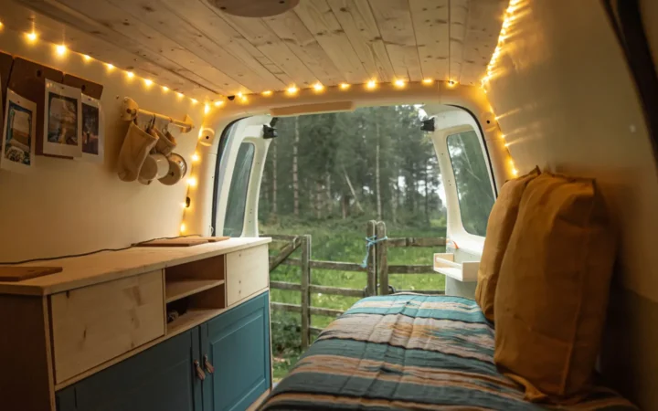 Camper van bed with pillows under warm string lights