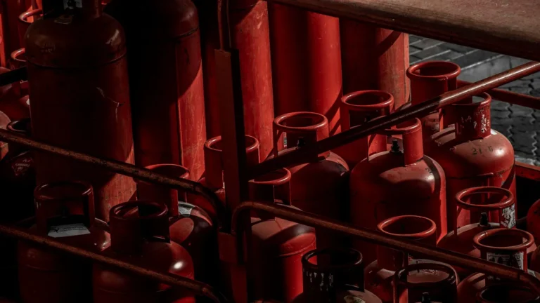 Rows of red propane cylinders stored upright in a rack