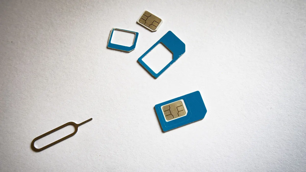 Physical SIM cards and an ejector tool on a white surface