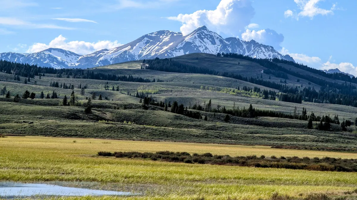 Snow-capped mountain rising above a grassy valley under blue sky