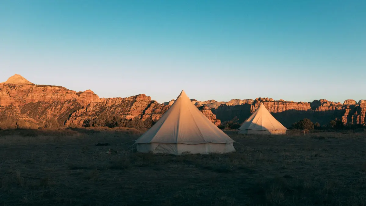 Canvas tents at a desert campsite glowing at sunset