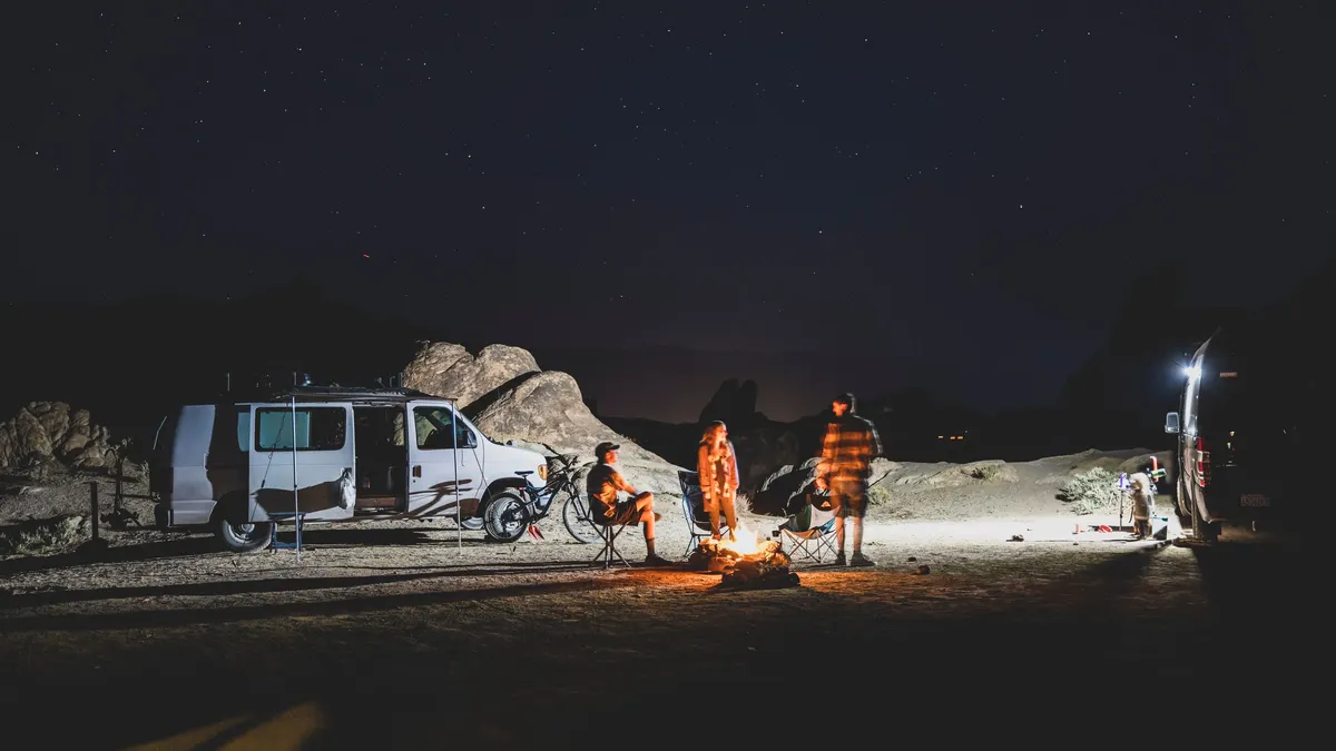 Camper vans and people at a desert campsite at night