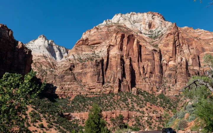 Red sandstone cliffs above a winding road and green trees